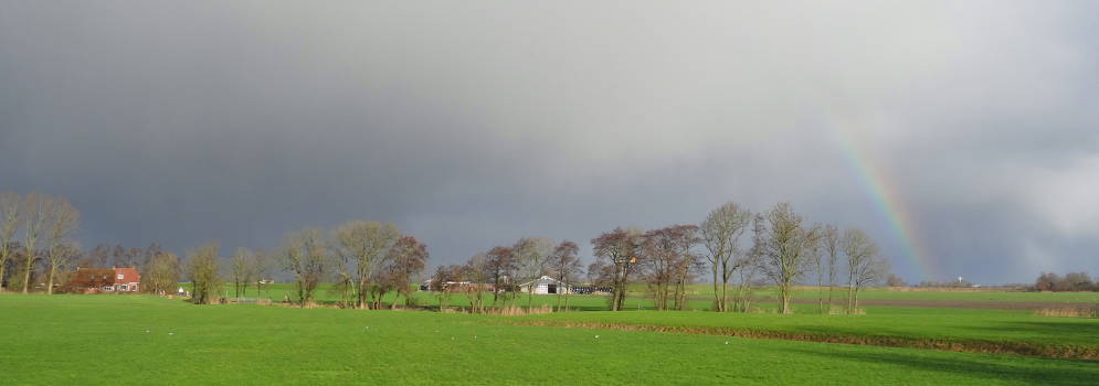 Regenboog en donkere wolken op het platteland van Groningen